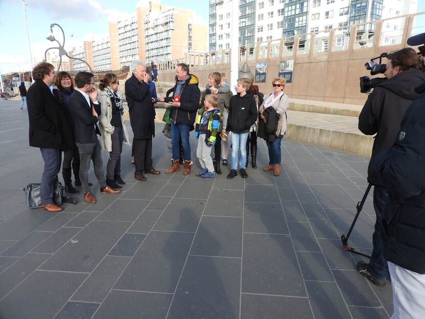 Op de pier van Scheveningen staat Adriënne van Sar tussen andere mensen voor de opnames van Piets weerbericht.