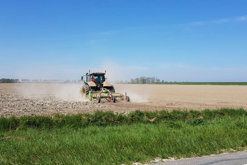 Agrariër aan het werk op het land met tractor en ploeg.