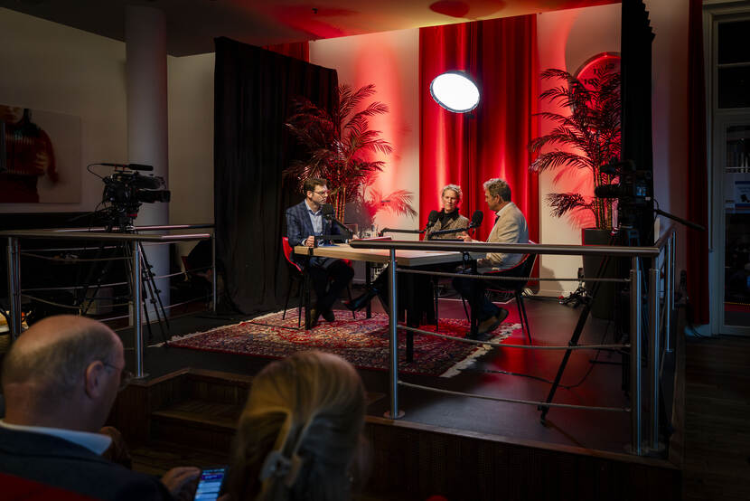 Drie mensen zitten aan een tafel en zijn in gesprek met elkaar