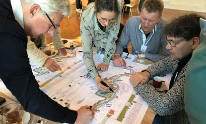 Vier mensen buigen zich over de kaart van het projectgebied Meanderde Maas en maken aantekeningen.