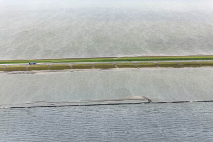 De Houtribdijk wordt versterkt. Een bovenaanzicht met op de foto de groene dijk (horizontaal door de foto heen) met water aan beide kanten.