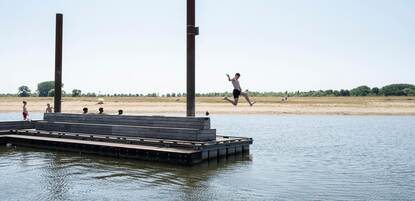 Een jongen neemt een sprong in het water tijdens de hete zomer in 2019. Het zwemwater in een nevengeul en recreatieplas langs de rivier de IJssel is nog van goede kwaliteit.